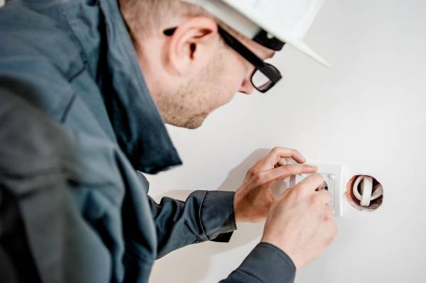 Elektriker som monterar ett vägguttag i samband med renovering av ett hus.